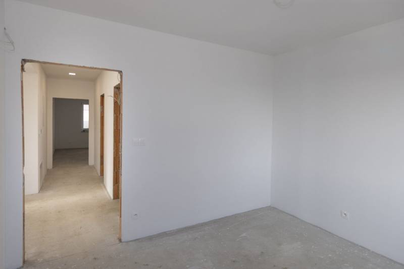 Empty room with white walls and a concrete floor in a family house.