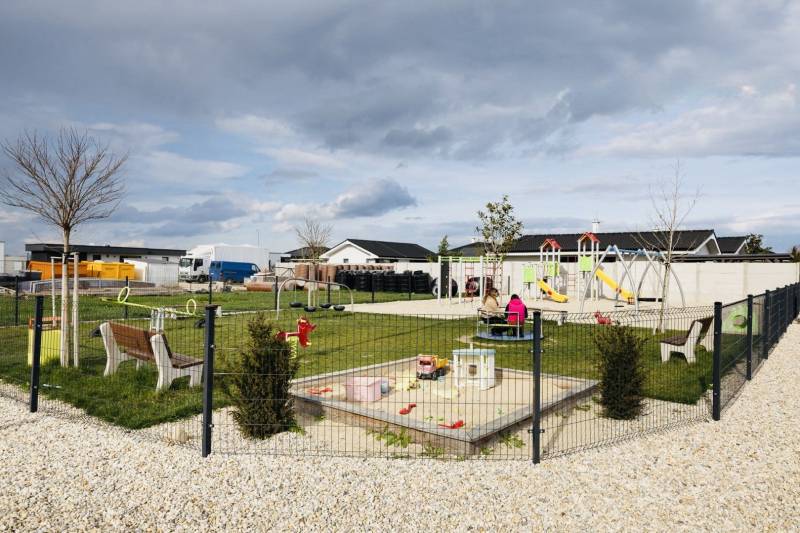 Playground in Galanta Košúty with climbing frames and a sandbox near family houses.