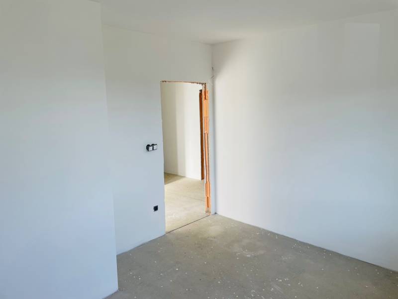 White wall with a door opening, concrete floor, ready for construction in a family house.