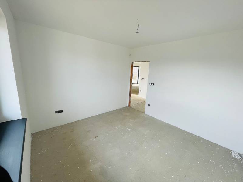 An empty room with white walls and an unfinished floor in a family house.