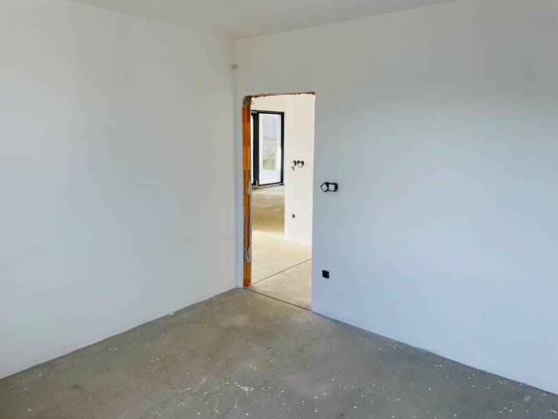 Empty room in a family house with a concrete floor and unfinished walls.