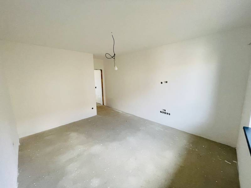 An empty room in a family house with an unfinished light bulb and white walls.