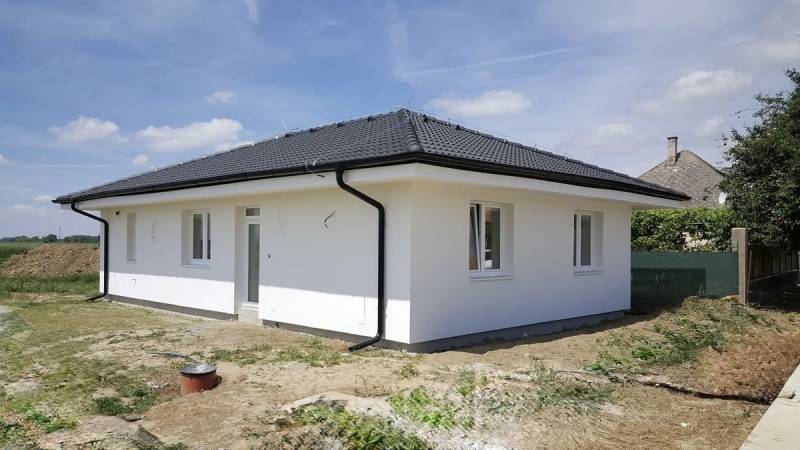 A family house in Western Slovakia with a white facade and a black roof.