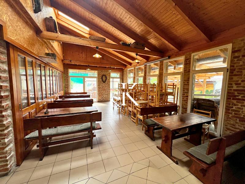 Wooden tables and chairs in dining areas with a brick wall and wooden ceiling.
