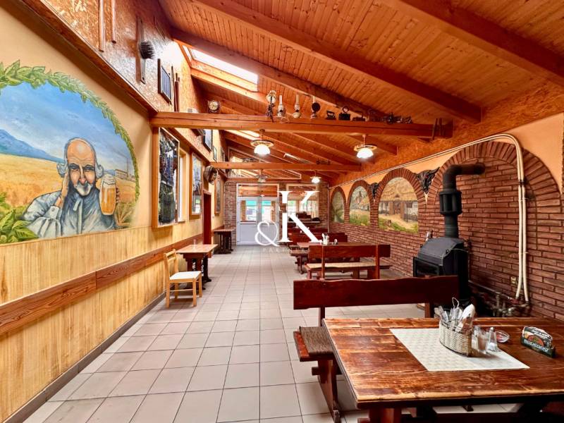Interior of dining spaces with wooden benches, decorative paintings, and a brick fireplace.