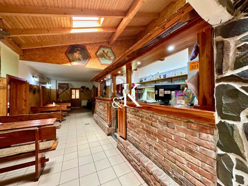 Interior of dining spaces with wooden benches, a bar, and decorative paintings on the walls.