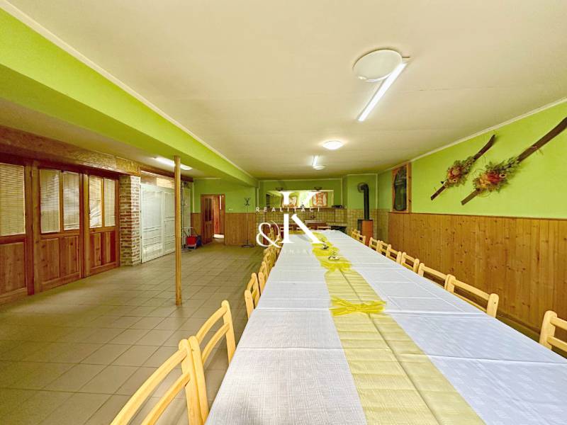 A long table with wooden chairs in a dining area with wooden paneling and decorations.