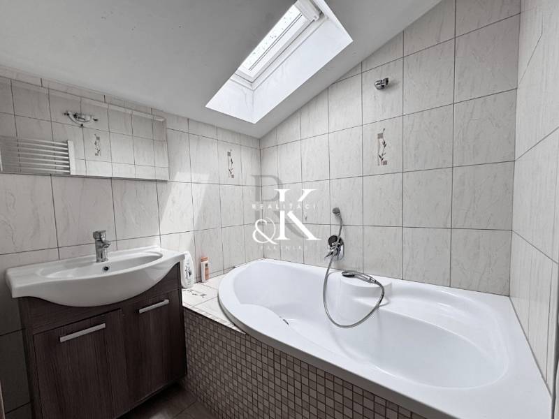 A bathroom interior with a skylight, sink, and bathtub.