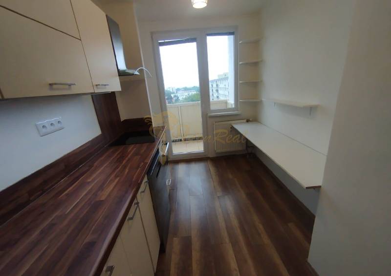 A kitchen in a 3-room apartment with a wooden countertop and access to a balcony.