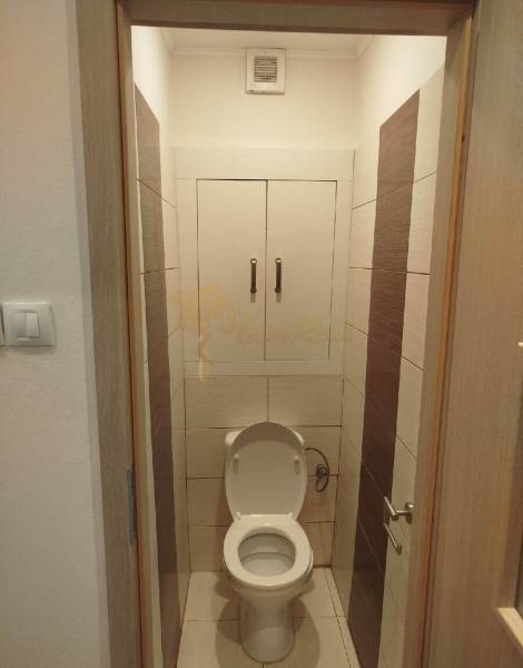 A toilet with white doors and brown tiles in a 3-room apartment.