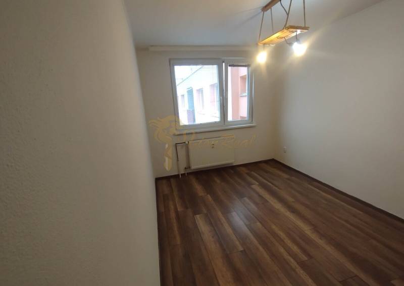 A room in a 3-room apartment with a wooden floor and a large window.