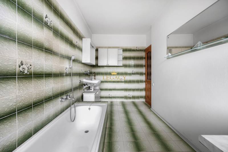 Bathroom in a family house with characteristic green tiles and a bathtub.