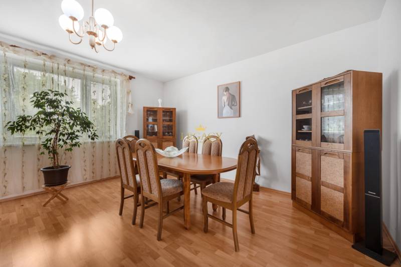 Dining area in a family house with wooden furniture and a plant by the window.