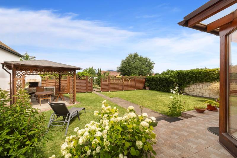 The garden of a family house in Vinosady with a gazebo, a deck chair, and flowers.