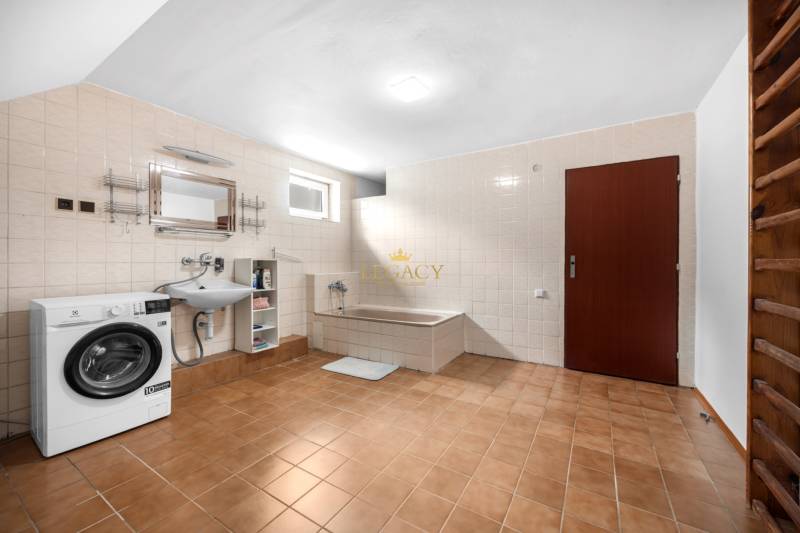 A bathroom in a family house with a bathtub, sink, and washing machine.