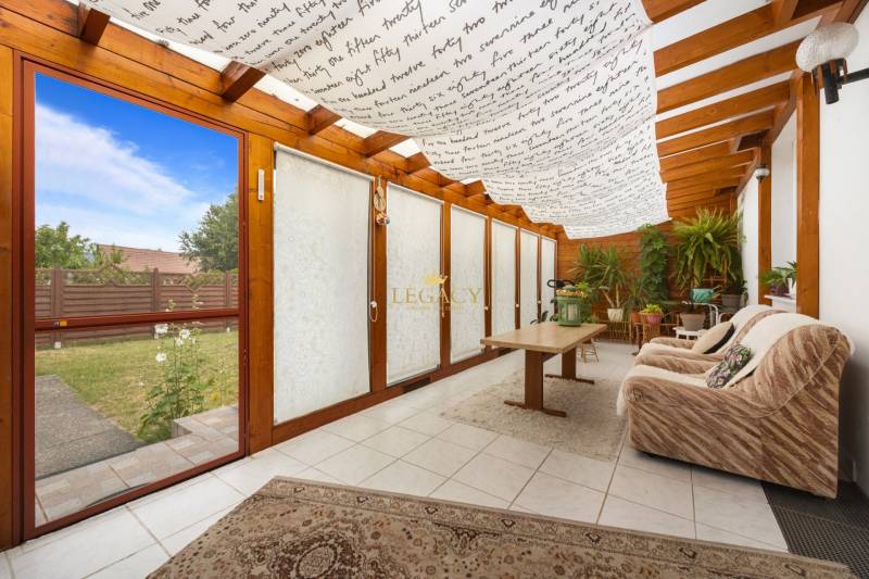 A winter garden in a family house with a sofa and plants, view of the lawn.