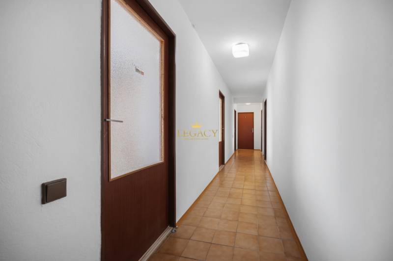 A hallway with brown doors and white walls, tiled floor in a family house.