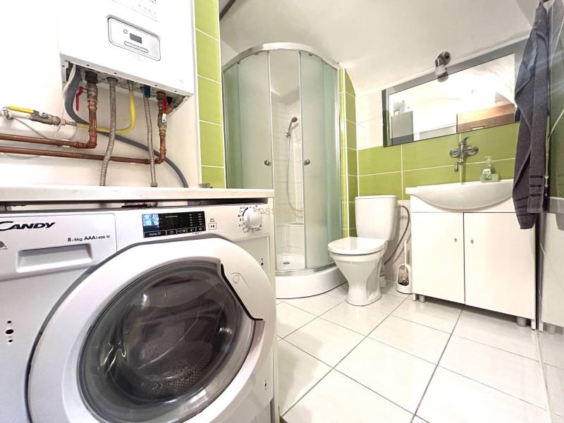 Bathroom with a shower, toilet, and washing machine in a 3-room apartment.