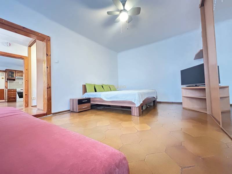 Bedroom with a bed, television, and sofa in a three-room apartment.