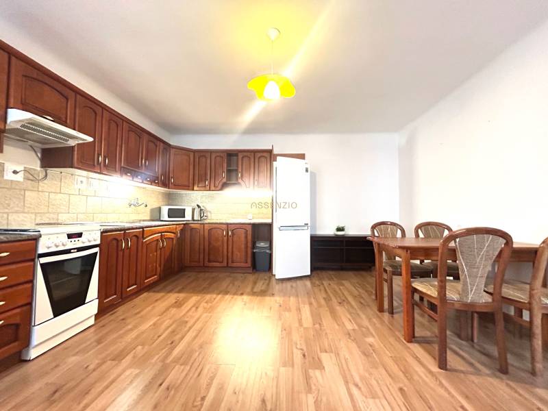 A spacious kitchen in a 3-room apartment with light wooden furniture and a dining table.