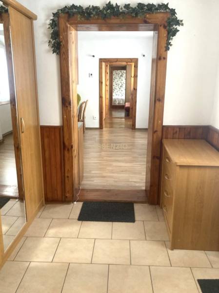The hallway of a 3-room apartment with wooden paneling and a mirror leads to other rooms.