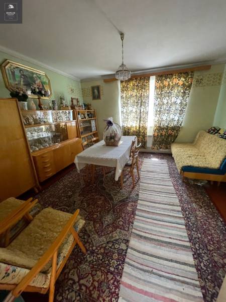 A traditionally furnished living room in a family house with carpets and curtains.
