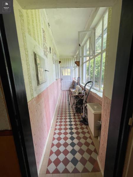 The interior of a porch in a family house with a tiled floor and a window wall.