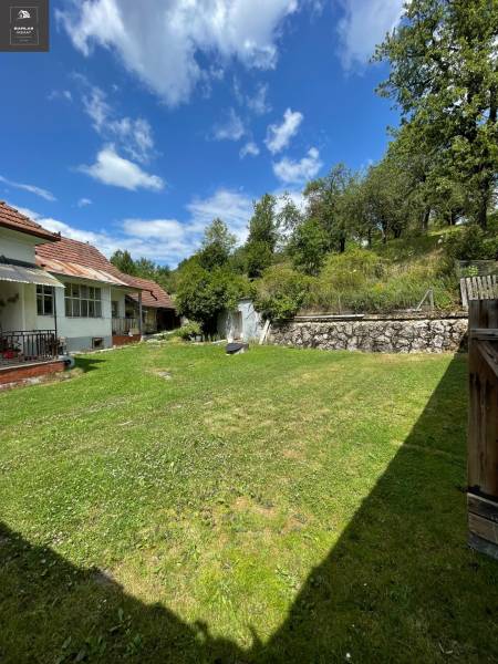 A family house in Horná Súča with a lawn, trees, and a clear sky.