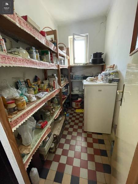 A pantry in a family house with shelves and a checkered pattern floor.