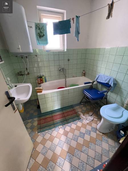 A bathroom in a family house with a bathtub, sink, toilet, and laundry on a line.