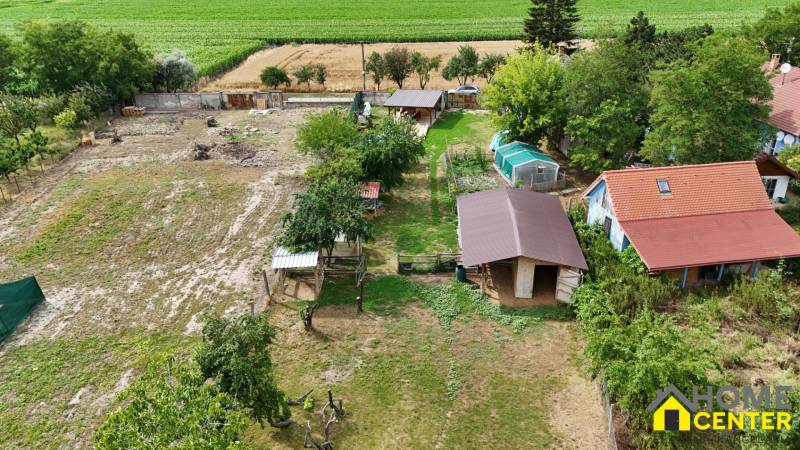 A garden in Kolárovo by a family house with shelters and a greenhouse surrounded by fields.