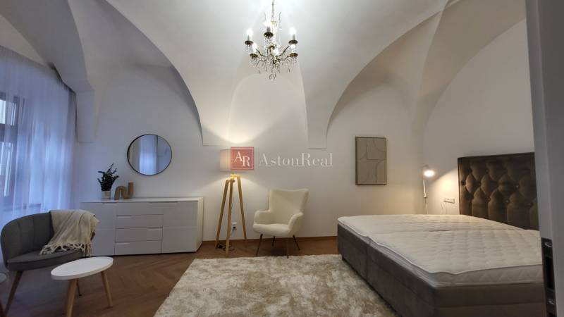 Bedroom in a 2-room apartment with a chandelier, armchair, and bed, in soft color tones.