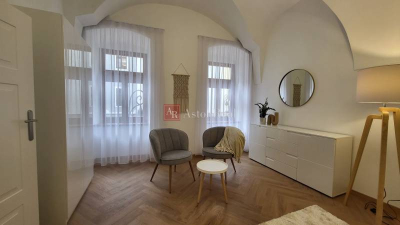 Interior of a 2-room apartment with chairs, a table, and a sideboard with decorations.