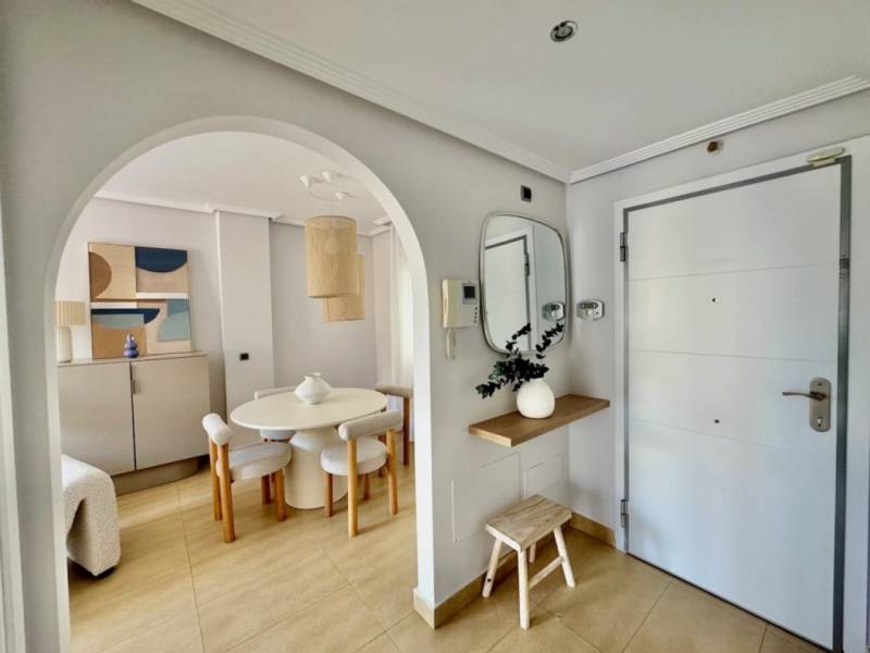 A stylish entrance hallway with an arched passage and light furniture in a holiday apartment.