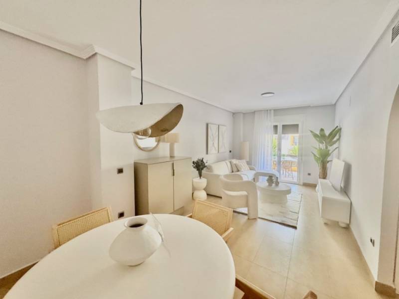 Spacious interior of a holiday apartment with light furniture and a dining table.