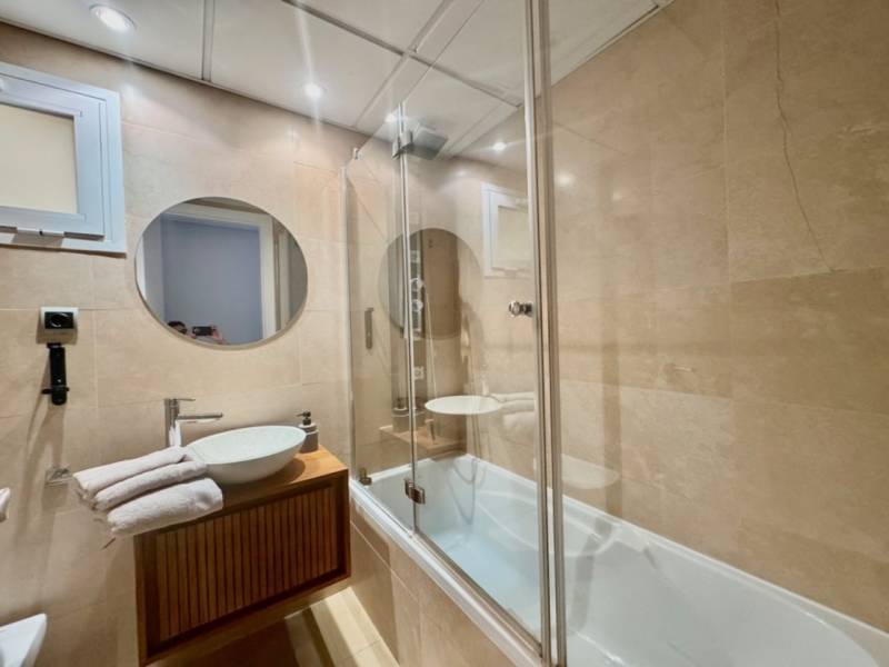Bathroom with a round mirror, shower corner, and sink in a Holiday Apartment.