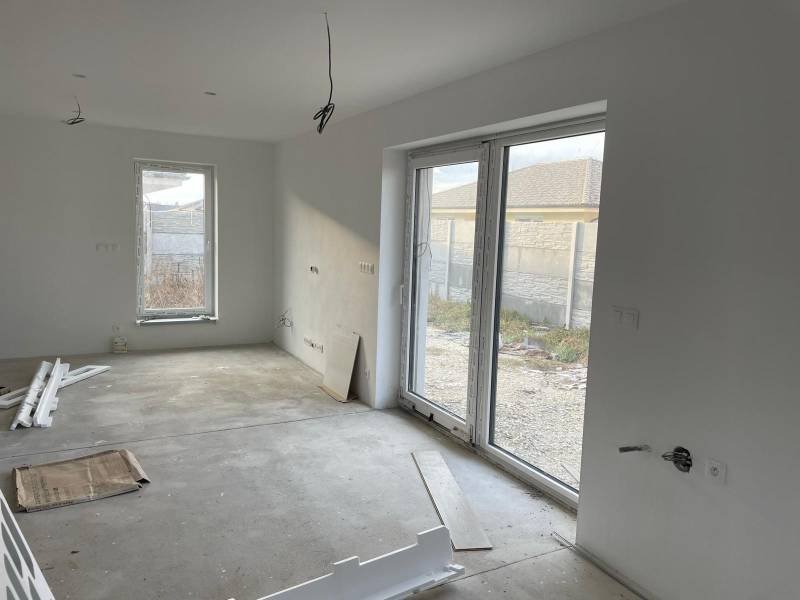 An empty room with large windows, tiles, and prepared cables - House construction.