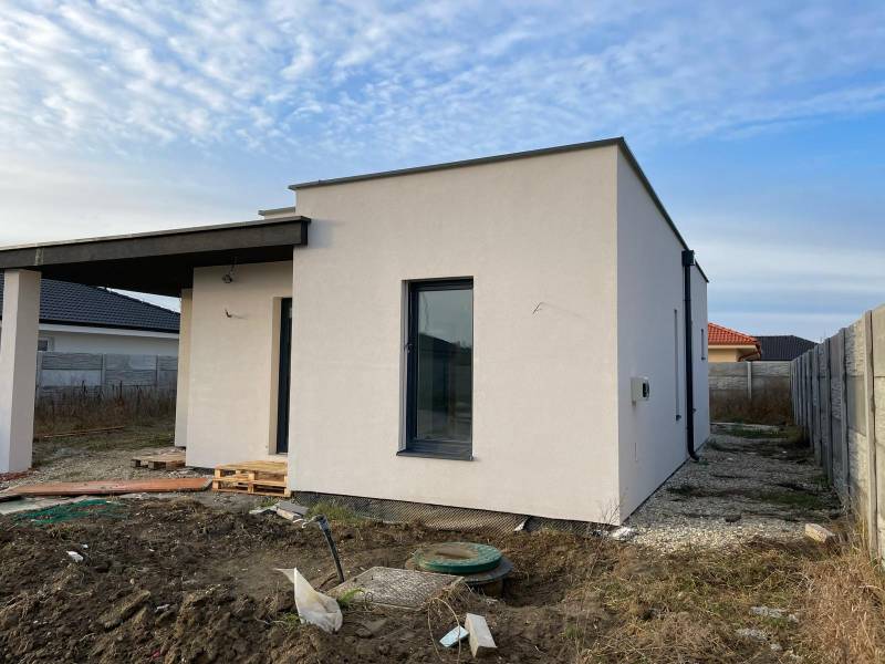 Construction of a house in Western Slovakia with a light facade and unkempt surroundings.