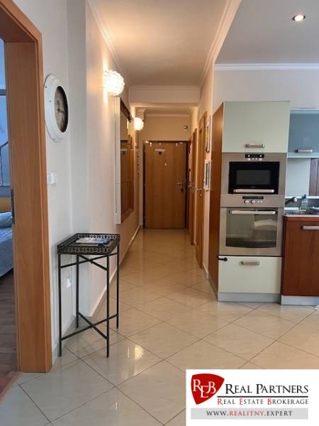 Hallway in a 3-room apartment with a kitchen and built-in appliances, light tiles.