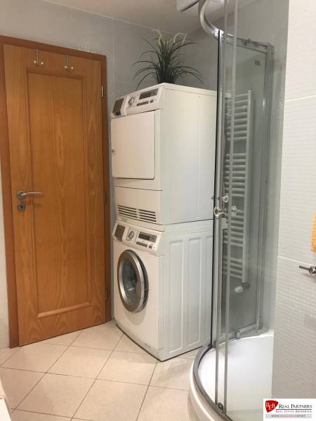 A bathroom in a 3-room apartment with a shower, washing machine, and dryer.