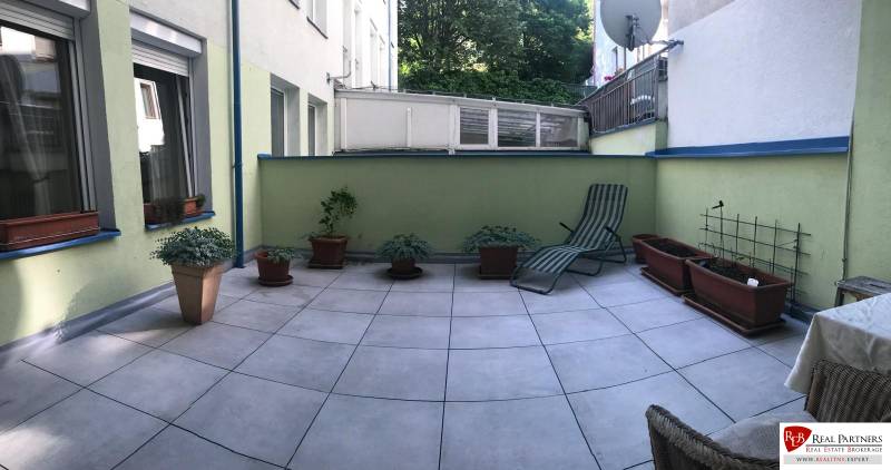Spacious terrace in a 3-room apartment with flower pots and a lounger for relaxation.