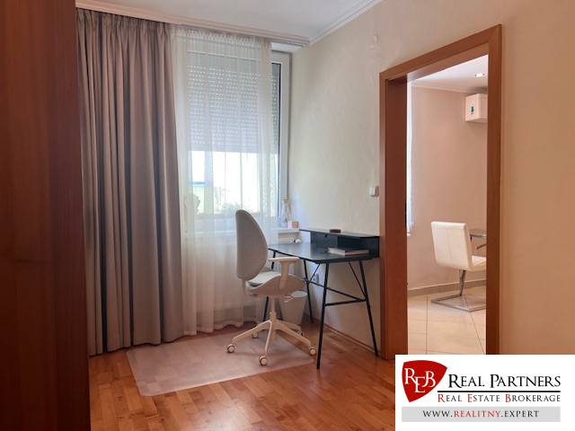 A workspace in a 3-room apartment with a white chair and a desk by the window.