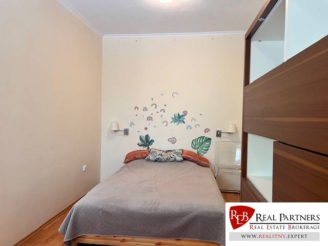 Bedroom in a 3-room apartment with a bed, wall decoration, and storage space.