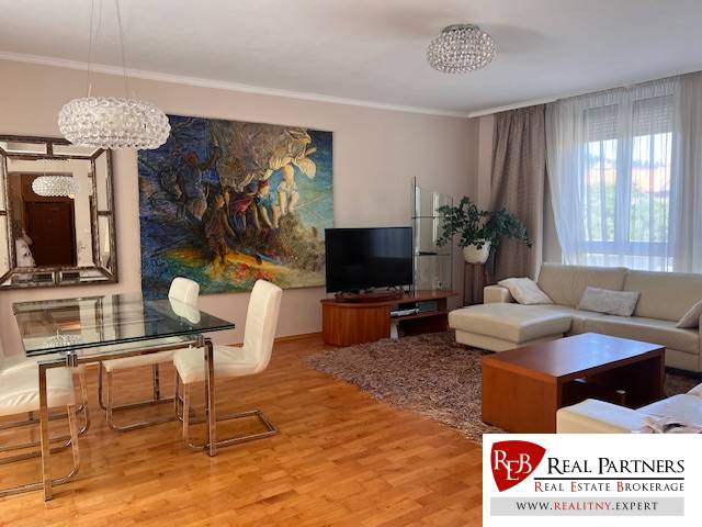 Living room in a 3-room apartment with a sofa, dining table, and a painting on the wall.