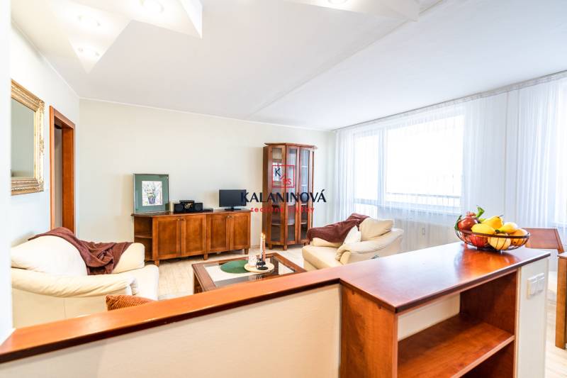 Living room with a sofa, wooden furniture, and a table with a bowl of fruit in a 3-room apartment.