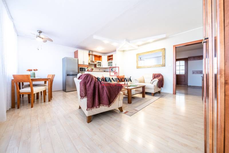 Living room in a 3-room apartment with wooden flooring, a sofa set, and a dining area.
