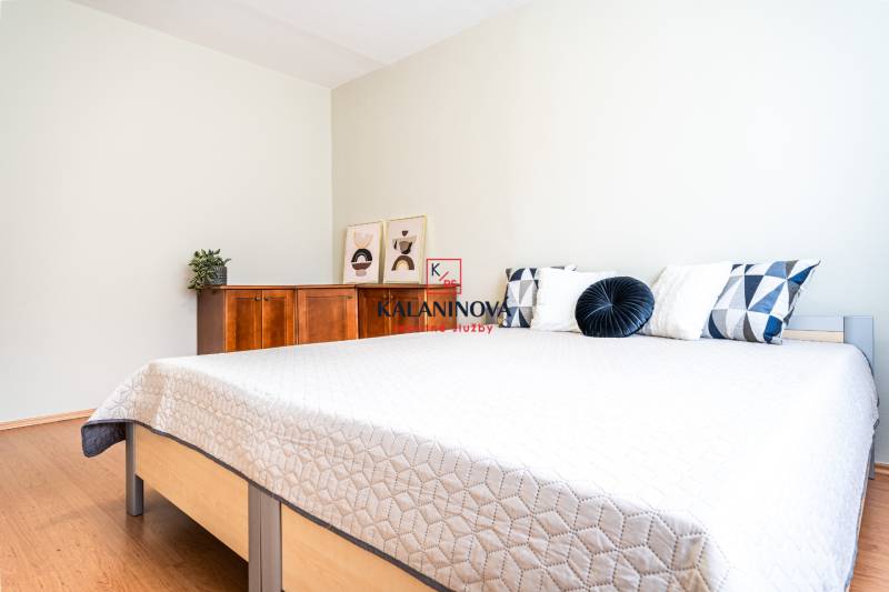 Bedroom in a 3-room apartment with a double bed and a wooden dresser.