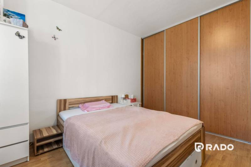 A bedroom with a bed, a nightstand, and a large built-in wardrobe in a 3-room apartment.