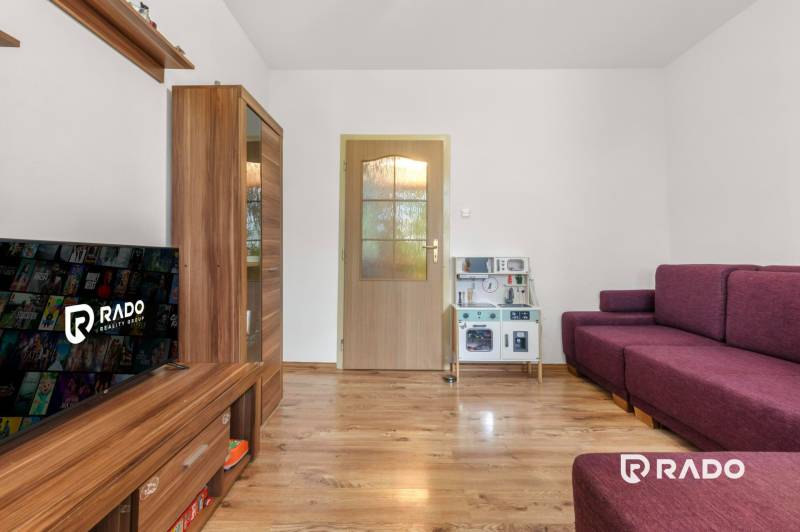 In the 3-room apartment, there is a television, wooden furniture, and a purple sofa.