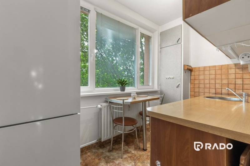 A kitchen in a 3-room apartment with a dining table and a view of greenery.
